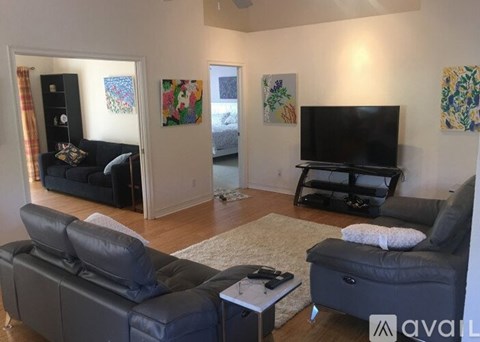 A living room with a black leather sofa and a television.