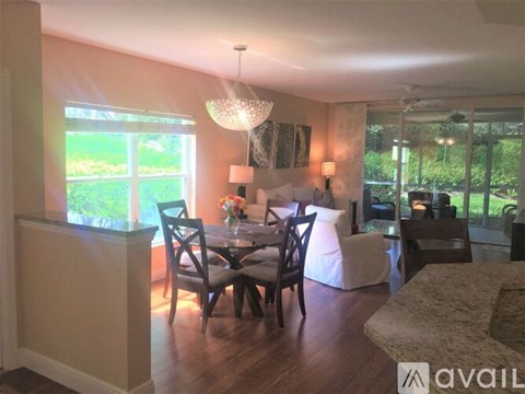 A dining room with a table set for four and a chandelier hanging from the ceiling.