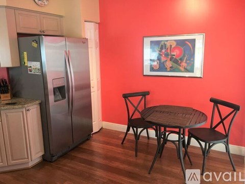 A kitchen with a refrigerator, table and chairs.