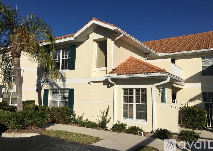 A house with a red tile roof and a palm tree in front.
