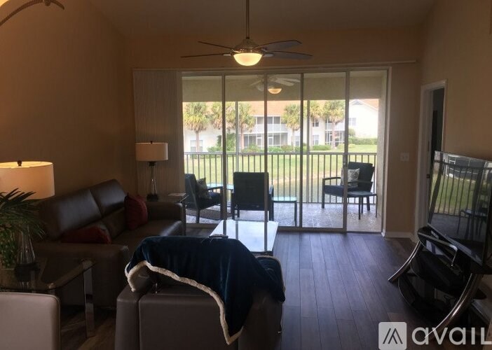 A living room with a couch, chairs, and a ceiling fan.