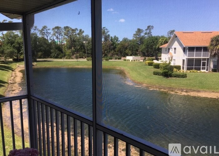 A house with a red roof is situated by a body of water.