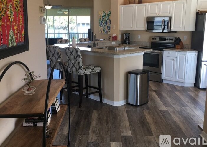 A kitchen with a wooden floor and white cabinets.