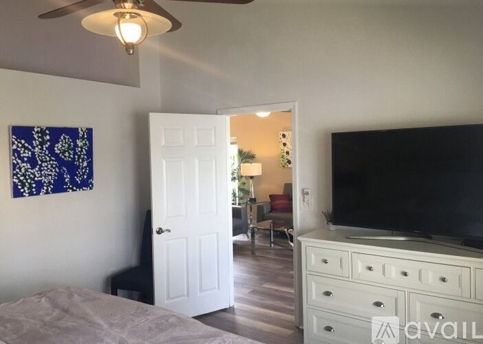 A bedroom with a bed, dresser, and television.