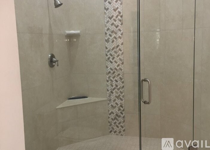 A shower area with a glass door and a tiled wall.