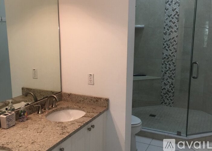 A bathroom with a sink, mirror, and shower.
