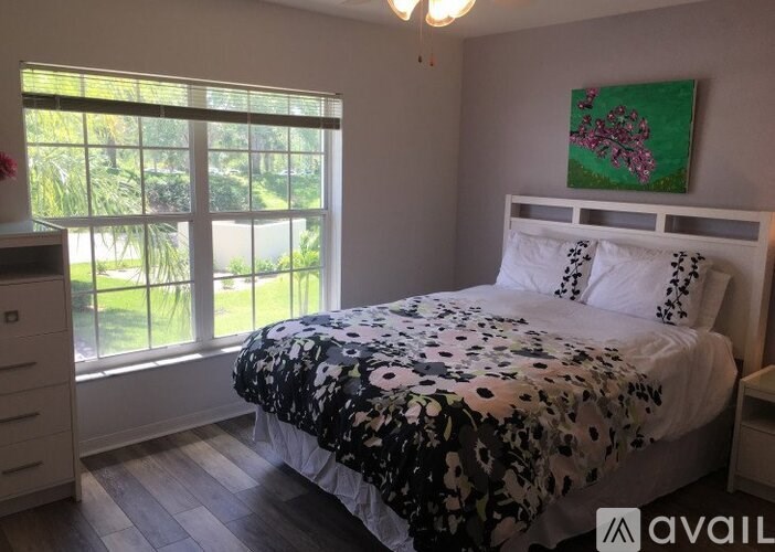 A bedroom with a large bed and a painting on the wall.