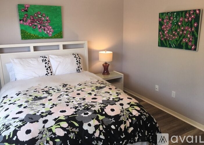 A bedroom with a floral bedspread and two paintings on the wall.