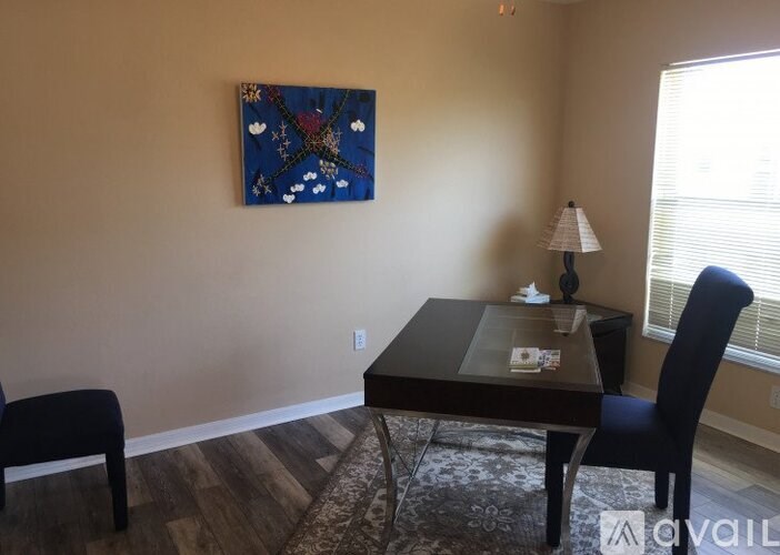 A dining room with a table, chairs and a painting on the wall.