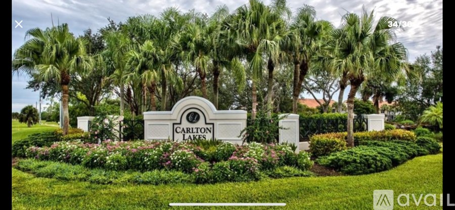 A sign for Carlton Lakes is surrounded by greenery.