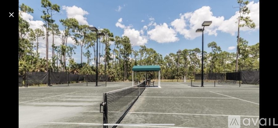 A tennis court surrounded by trees and a fence.