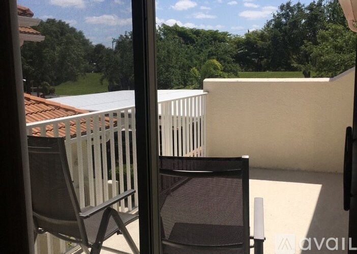 A balcony with a chair and a table with a glass top.