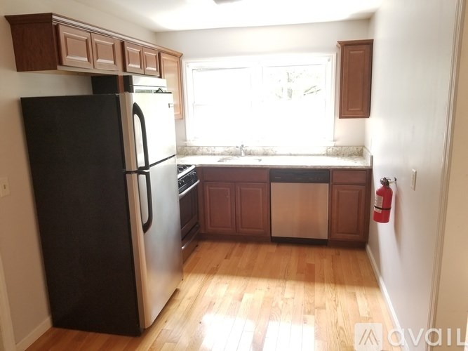 A kitchen with a black fridge and wooden cabinets.