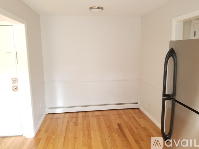 A kitchen with a white fridge and wooden floors.