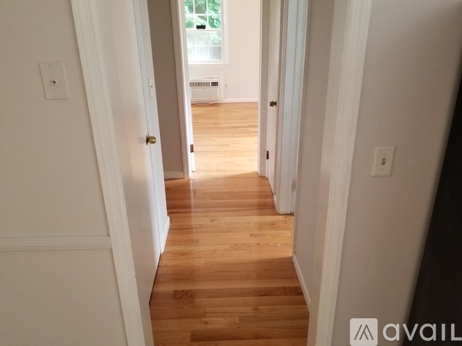 A hallway with wooden floors and white walls.