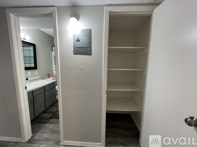A white door with a silver handle and a small square light switch on the wall.