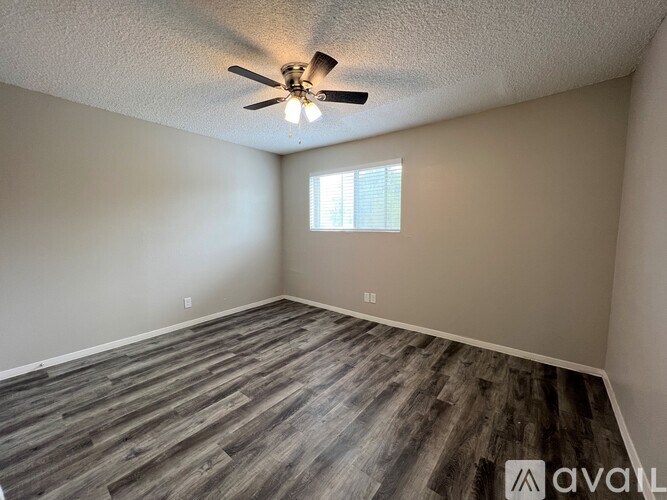A room with a ceiling fan and wooden flooring.
