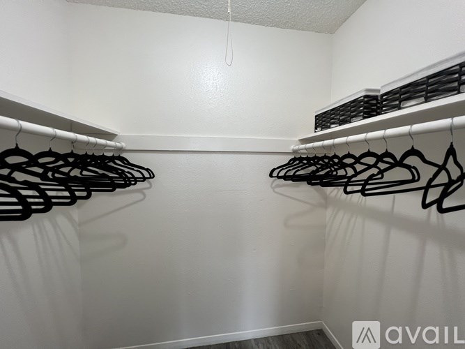 A row of black hangers on a white wall.