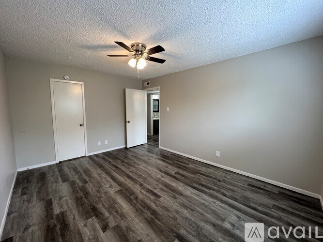A room with a ceiling fan and wooden flooring.