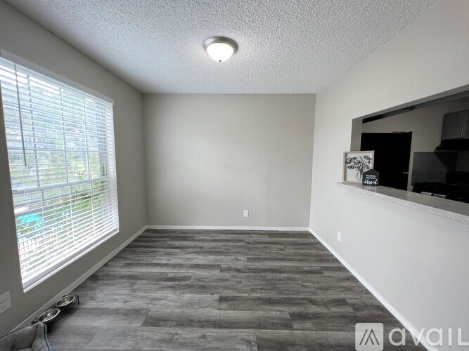 A room with a grey floor and a window with blinds.