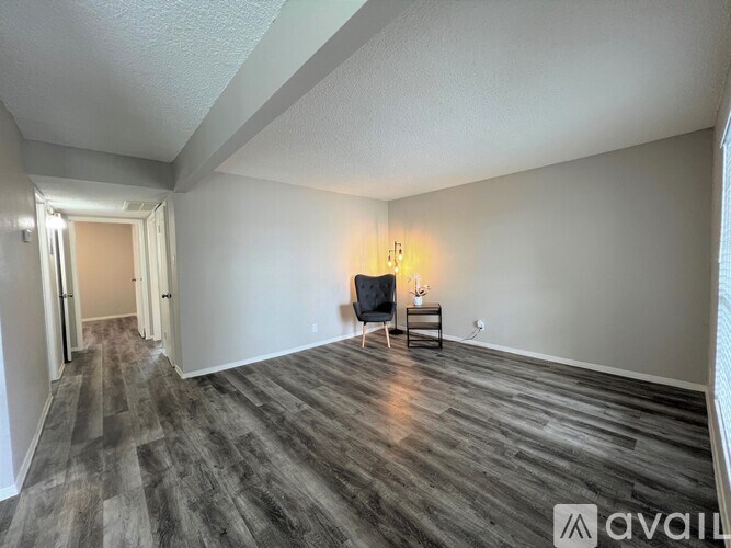 A room with wooden flooring and a chair with a lamp on it.