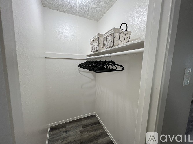 A white closet with a basket and hangers on the shelf.