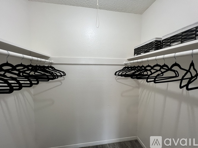 A row of black hangers on a white wall.