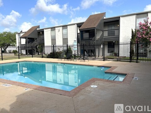 A swimming pool surrounded by a black fence and a building in the background.
