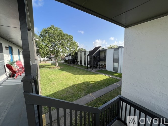 A balcony view of a grassy area with trees and a row of houses.