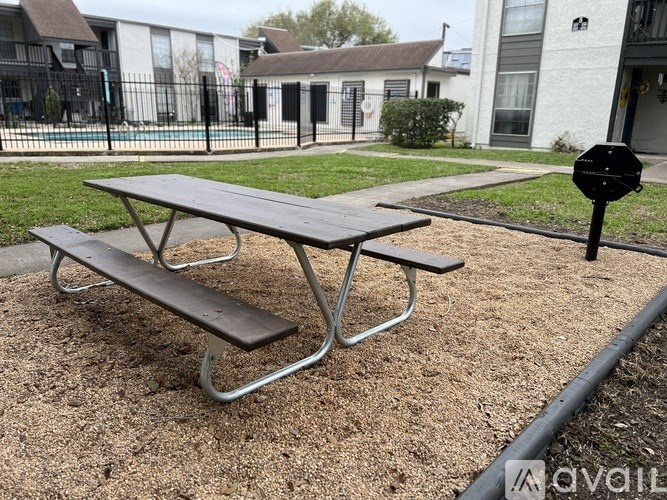 A picnic table with a bench is in the foreground of a residential area.