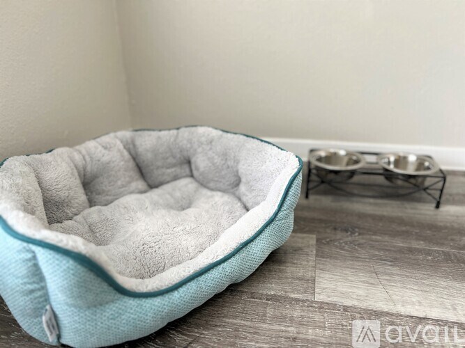 A blue pet bed with a grey cover is on a wooden floor.