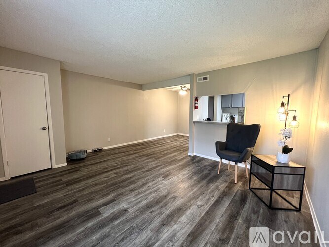A room with a black chair and a wooden floor.