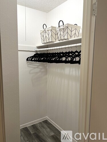 A white closet with black hangers and white baskets on top.