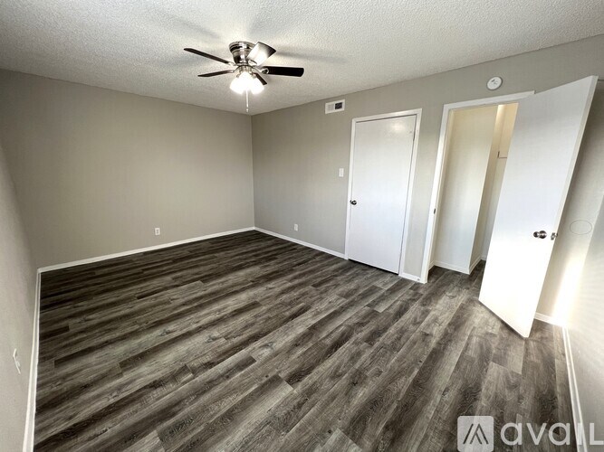 A room with a ceiling fan and wooden flooring.