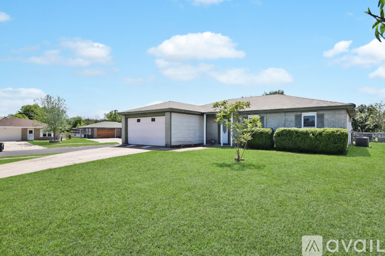 A house with a white garage door is surrounded by a well-maintained lawn.