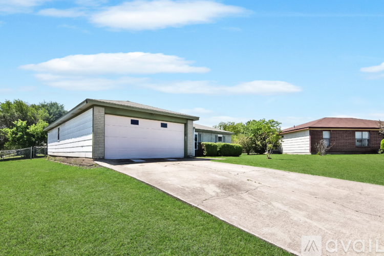 A detached garage with a white door is situated in a grassy area.