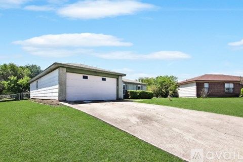 A detached garage with a white door is situated in a grassy area.