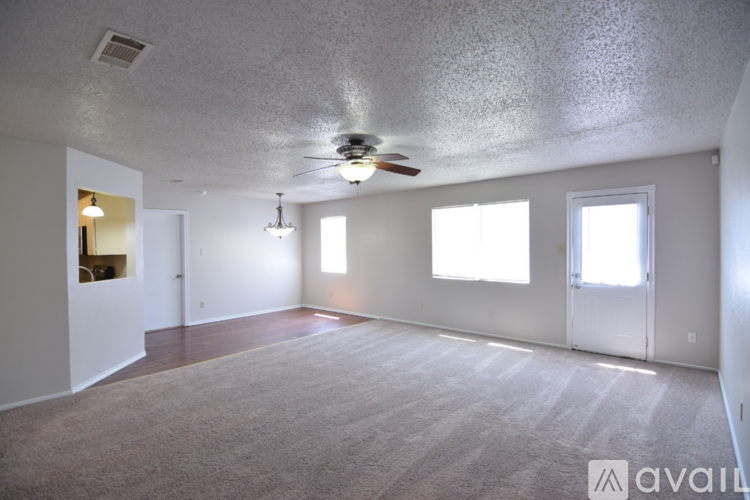 A spacious room with a carpeted floor and a ceiling fan.