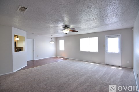 A spacious room with a carpeted floor and a ceiling fan.