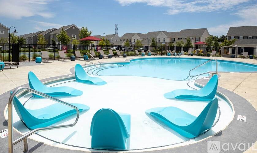 A round swimming pool surrounded by blue lounge chairs.