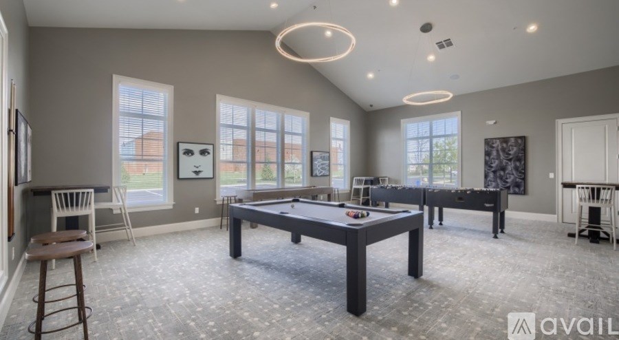 A spacious room with a pool table and a bar stool.