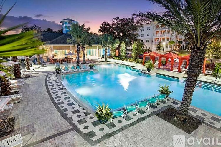 A large outdoor swimming pool surrounded by palm trees and lounge chairs.