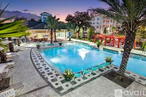 A large outdoor swimming pool surrounded by palm trees and lounge chairs.