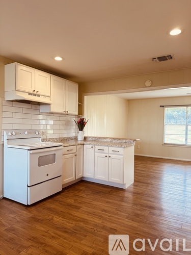 A kitchen with white appliances and cabinets with a logo that says "avaiL".