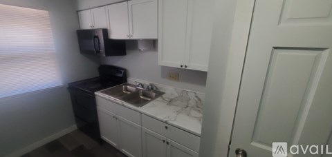 A kitchen with white cabinets and a black dishwasher.