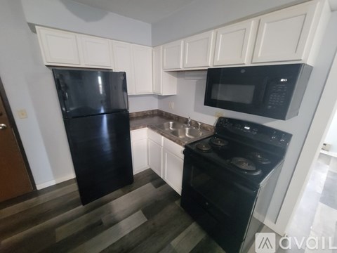A black fridge and microwave in a kitchen with white cabinets.