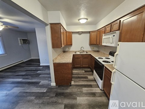 A kitchen with white appliances and wooden cabinets.