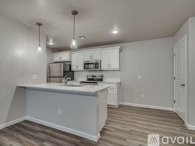 A kitchen with white cabinets and a white island with a sink.