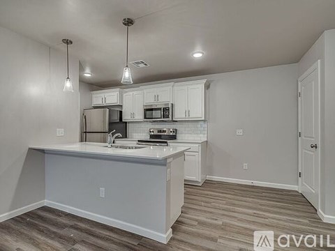 A kitchen with white cabinets and a white island with a sink.