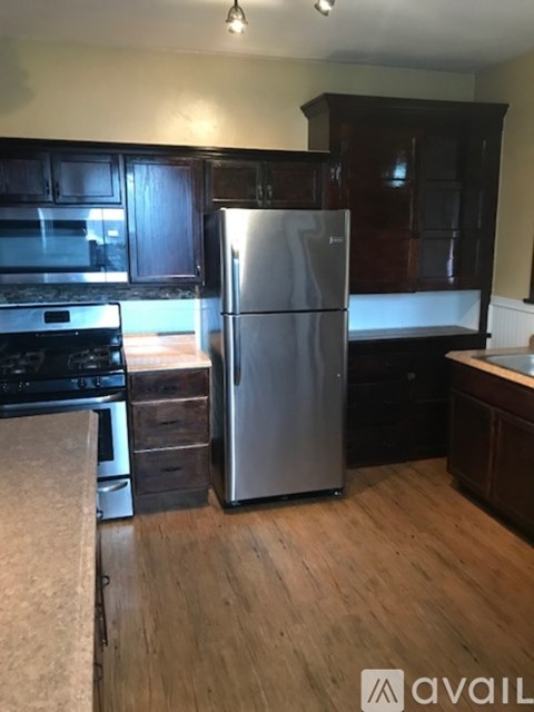 A kitchen with a refrigerator, stove, and cabinets.